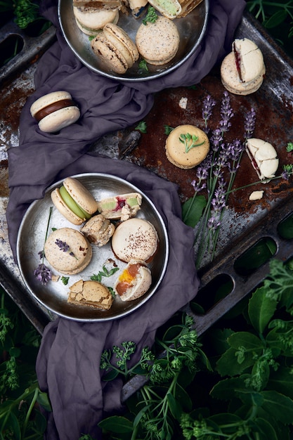 Photo macaroons on an old baking tray and a lavender flowers as a decoration among green bushes. top view.