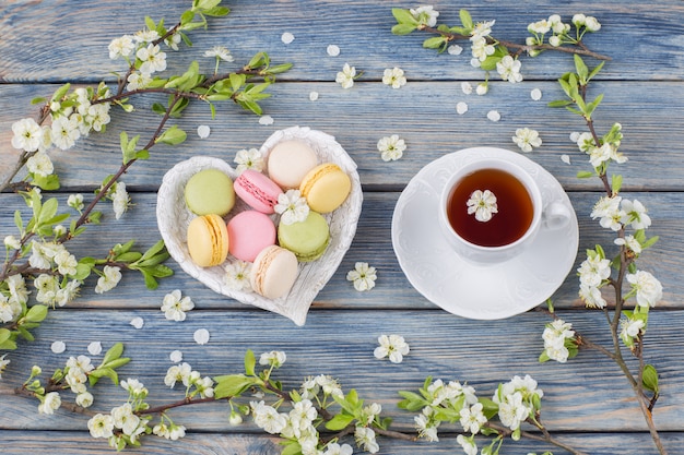 macaroons and tea in a cup, cherry branches in the form of a frame