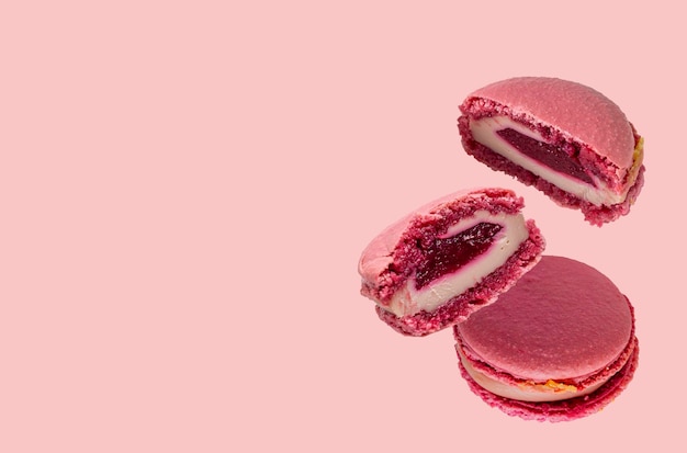 Macaroons with fruit filling on pink background selective focus copy of space