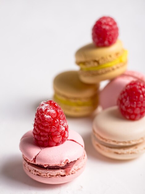 Macaroons with raspberries on top on white background