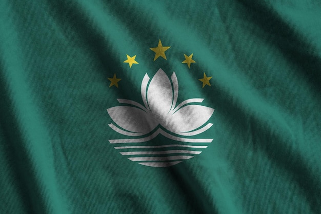 Macau-vlag met grote vouwen die van dichtbij onder het studiolicht binnen zwaaien De officiële symbolen en kleuren in banner