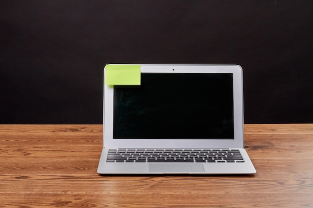 Macbook air laptop and attached sticky note for copy space notebook device on wooden desk