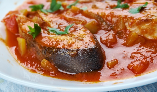 Foto il machcha besarou, pesce fritto marinato nella curcuma e cotto in senape, aglio e pomodori è un piatto tipico di oriya