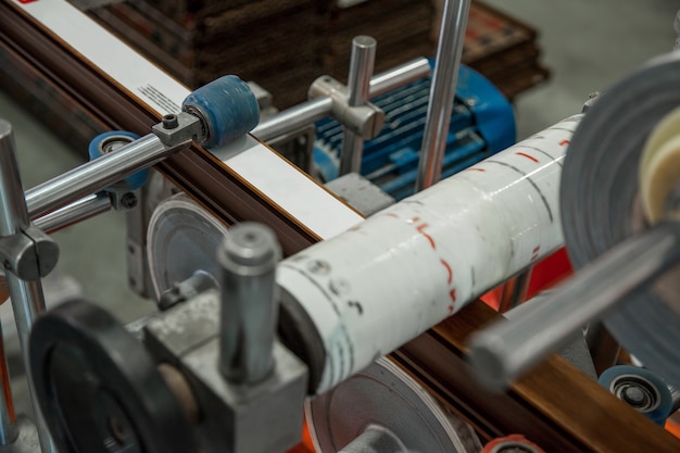 The machine glues the ribbon with the print on the profile Production of PVC profile