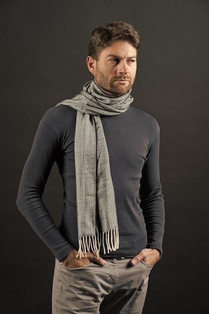 Macho in sweater scarf with hands in pockets