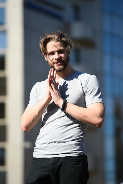 Macho with beard and haircut in grey tshirt standing