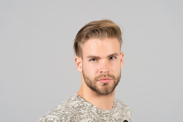 Macho with bearded face, beard. Man with blond hair, haircut. Grooming and hair care in beauty salon, barbershop. Fashion, style and trend concept.