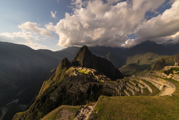 Machu picchu illuminato dalla calda luce del tramonto. ampio angolo di vista dalle terrazze sopra con cielo e sole.