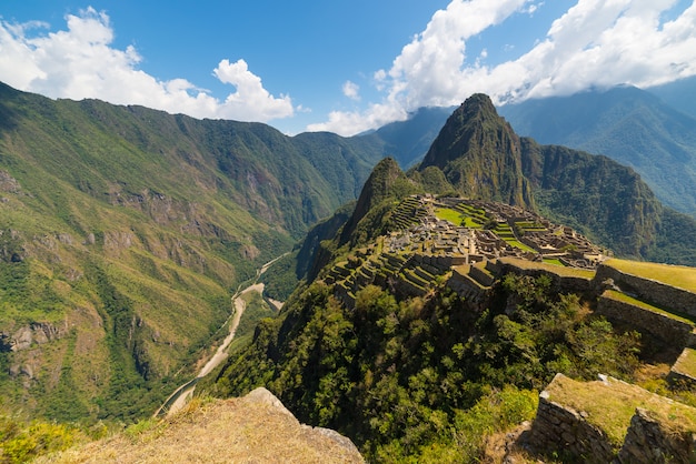 Machu Picchu verlicht door het zonlicht. Brede hoekmening van de terrassen hierboven met toneelhemel.