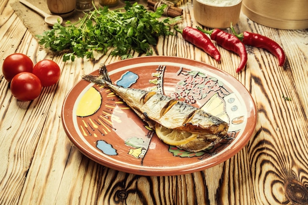 Mackerel scomber baked with lemon and garlic in plate on wooden background