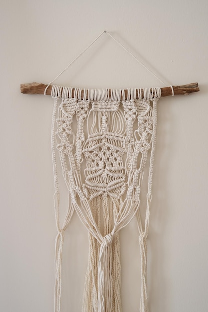 Macramé gemaakt met witte draden die aan de muur hangen.Macramé in verschillende patronen.