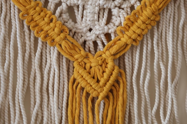 Macramé gemaakt van gele, witte en beige draden.