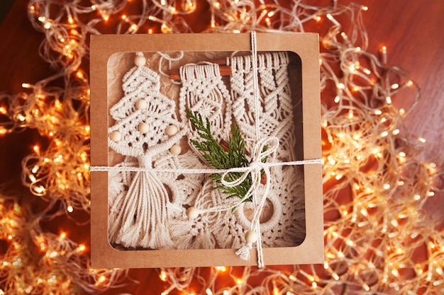 Macrame kerstdoos met speelgoed op donkere achtergrond Natuurlijke materialen katoendraad houten kralen en stok Eco-decoratie ornamenten handgemaakt decor Winter- en nieuwjaarsvakantie