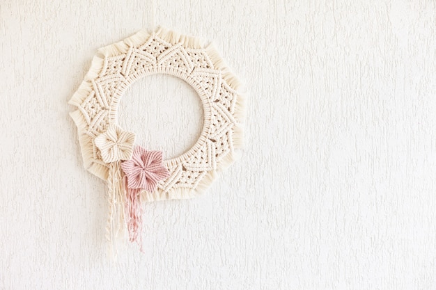 macramé krans met katoenen bloemen op witte decoratieve gipsen muur