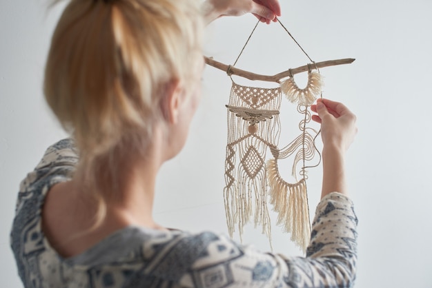 Macrame. Women's hobby. The girl makes a canvas of threads