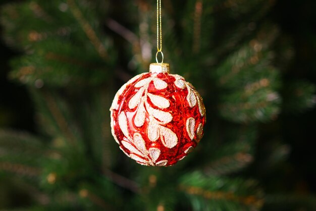 Macro close-up van enkele kerst rode decoratieve ornament bal opknoping op kerstboom met onscherpte...