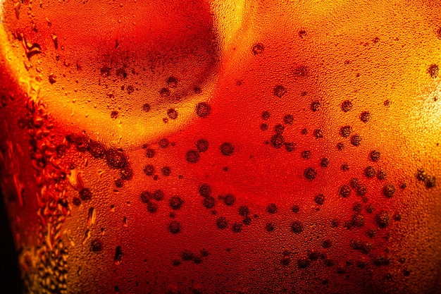 Foto struttura della cola macro, cola con sfondo di ghiaccio alimentare, primo piano della cola, elemento di design. bollicine di birra,