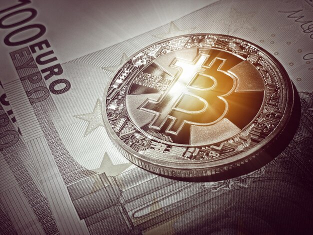 Photo macro glowing bitcoin over euro banknotes cyrptocurrency trading and exchange toned photograph