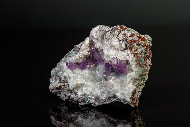 Macro mineral amethyst stone in rock on a black background