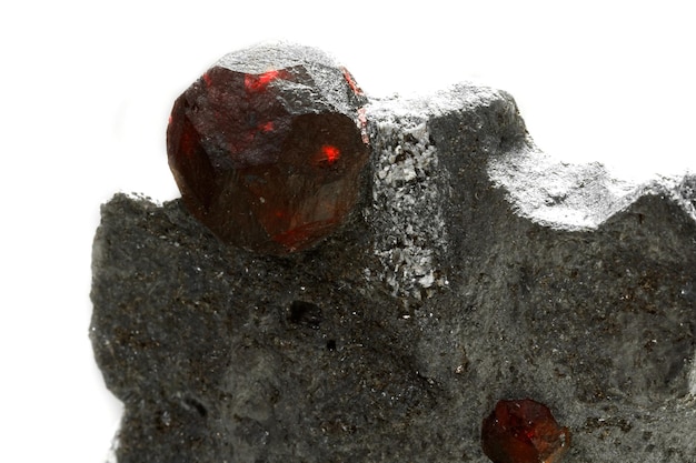 Macro mineral stone garnet in the rock on a white background