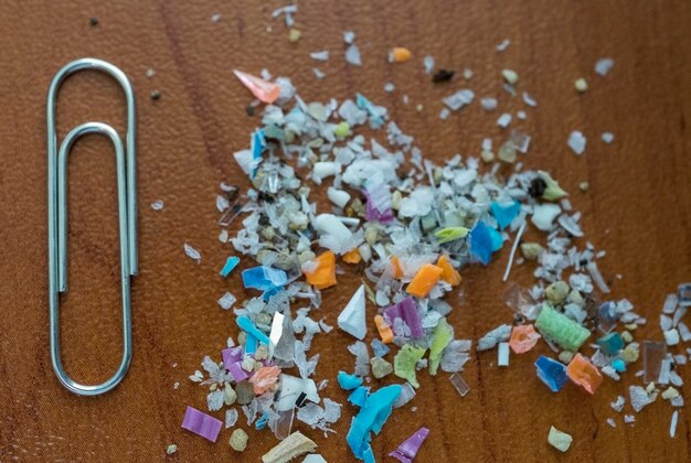 Macro-opname van microplastics met een paperclip voor maatvergelijking