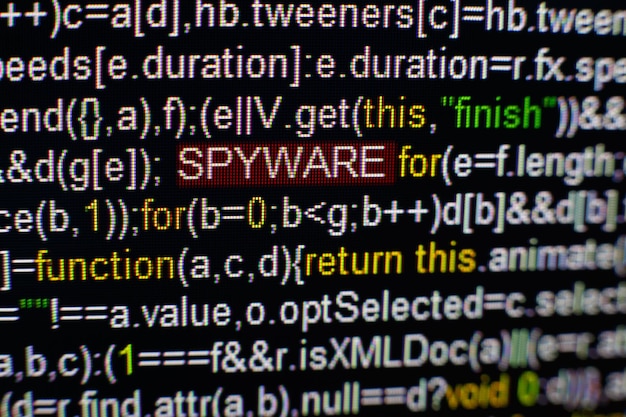 Photo macro photo of computer screen with program source code and highlighted spyware inscription in the