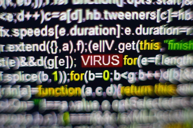 Macro photo of computer screen with program source code and highlighted virus inscription in the