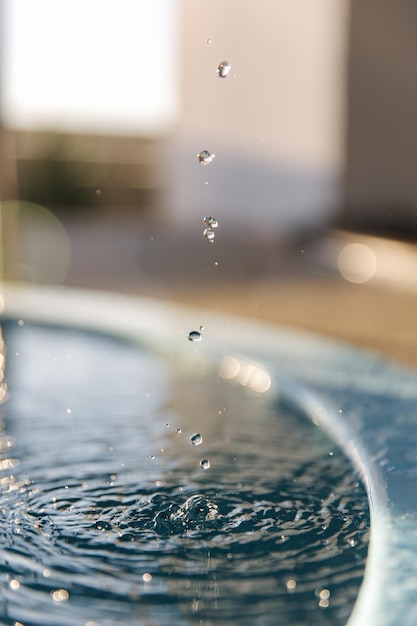 태양을 반사하는 푸른 물이 파문을 일으키는 맑은 수영장으로 물방울이 떨어지는 매크로 사진