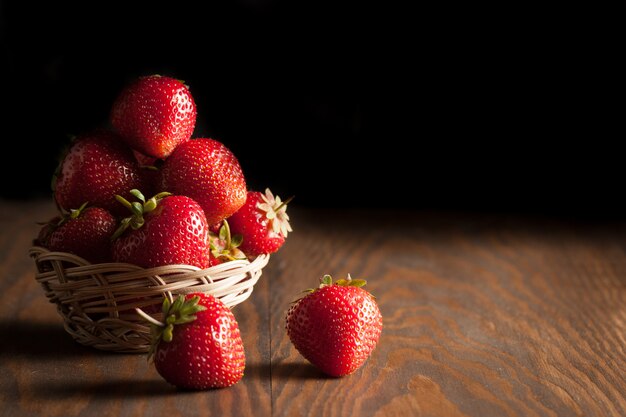 Macro photo of fresh ripe red strawberry in a wooden bowl on rustic background. Organic natural products.