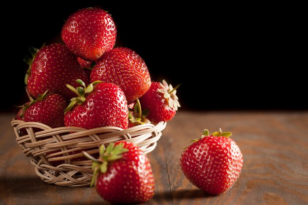 Macro photo of fresh ripe red strawberry in a wooden bowl on rustic background. Organic natural products.