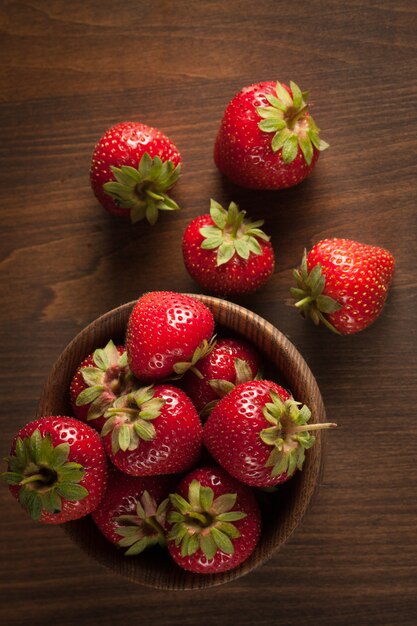 Macro photo of fresh ripe red strawberry in a wooden bowl on rustic background. Organic natural products.