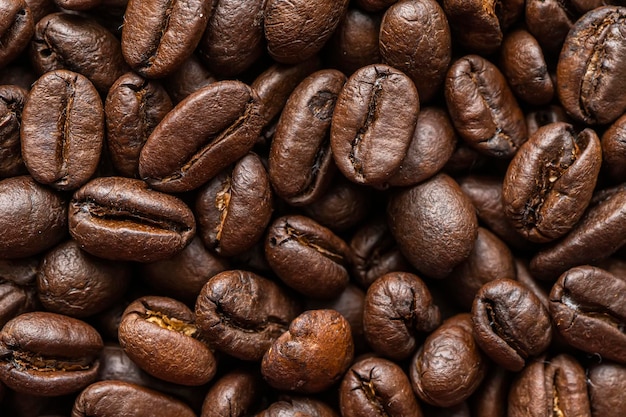 A macro photo of fried brown coffee beans on the table Coffee beans background Background of roasted coffee beans