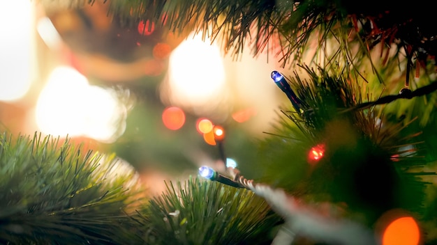 Macro photo of Glowing Christmas tree lights garlnd on fir tree branch