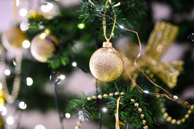 Macro photo of golden ball and light garland on Christmas tree