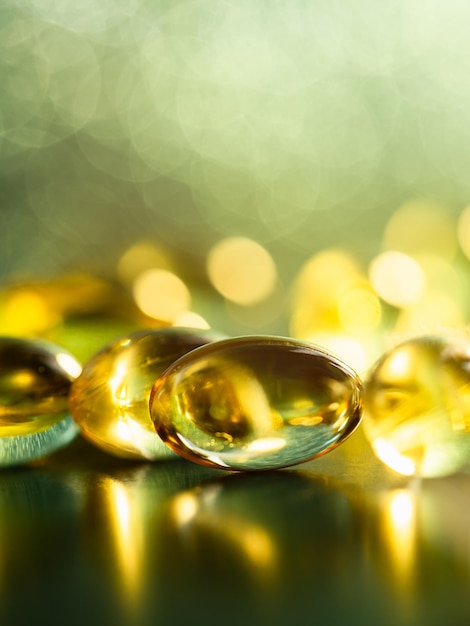 Macro photo of a handful of fish oil capsules with yellow defocused lights