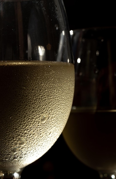 화이트 와인 두 잔의 매크로 사진입니다. 차가운 포도주가 담긴 두 잔과 그 위에 결로와 방울