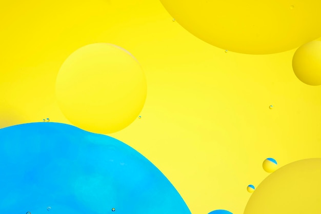 Macro photo with circles oil droplets water surface abstract blue and yellow background with oil bubbles