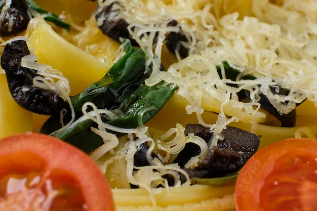 Macro photo with shallow depth of field of pasta with parmesan, chopped olives and basil