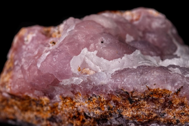 Macro pink Smithsonite mineral stone on microcline on black background