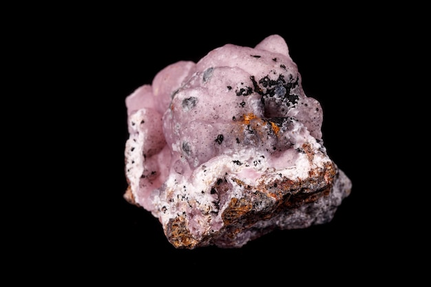 Macro pink Smithsonite mineral stone on microcline on black background