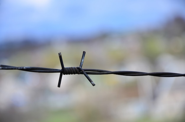 Macro shot of an element of old and rusty barbed wire with a blurred background.