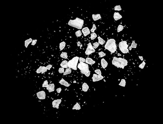 Photo macro shot of falling and flying salt crystals isolated on black