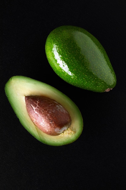 Macro shot of fresh avocados cut in a half on the black background.