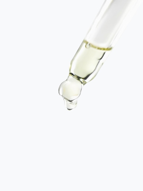 Photo macro shot of a glass pipette filled with cosmetic oil on a white background