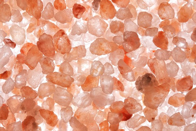 Macro shot of illuminated pink salt against light background showcasing intricate crystalline structures in delicate hues