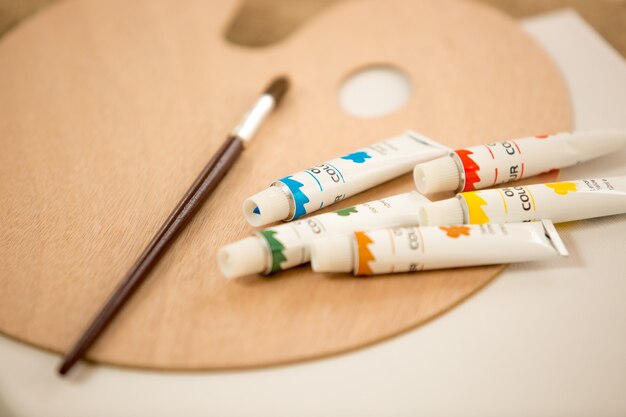 Macro shot of oil paint tubes an paintbrush lying on color pallet