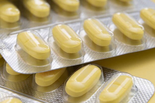 Macro shot of yellow pills on yellow background.