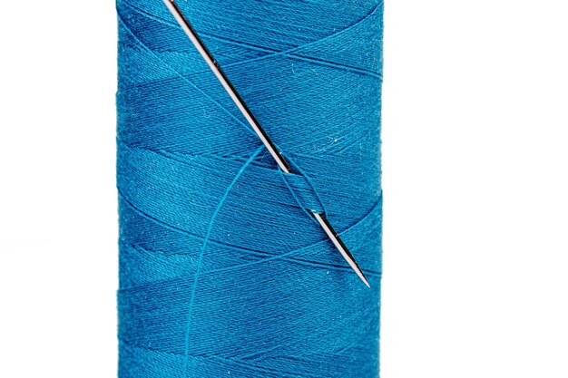 Macro skein of blue thread with a needle on a white background