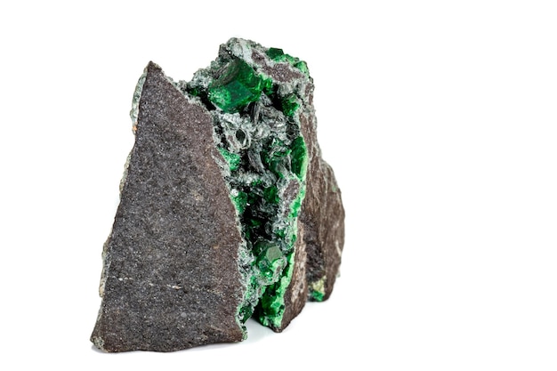 Macro stone garnet mineral Uvarovite in rock on a white background