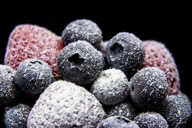 Macro view of frozen berries: strawberry, blueberry on dark background